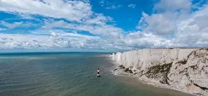 A panorama view of the Beachy Head Lighthouse in the English Channel and the white cliffs of the Jurassic Coast