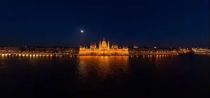 Quai Prints: Panoramic aerial drone shot of front facade of Hungarian Parliament with lights on in Budapest night