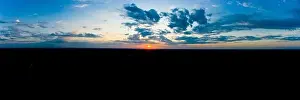 Panoramic aerial view of beautiful green tropical forest with mountains and majestic blue sky and clouds. Sunset