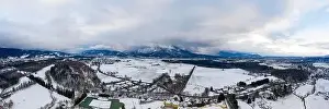 Snow Mountain Prints: Panoramic aerial view of Salzburg outskirts snowy villages during sunset hour with clouds after snow storm in winter
