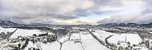 Snow Mountain Prints: Panoramic aerial view of Salzburg outskirts snowy villages during sunset hour with clouds after snow storm in winter