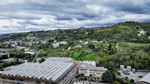 A panoramic view of Alba, Italy features rolling green hills interspersed with residential buildings and rural areas
