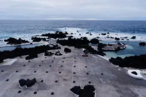 Natural Pools Prints: Empty parasol stands on concrete with volcanic rock and crashing waves at Porto Moniz natural pools