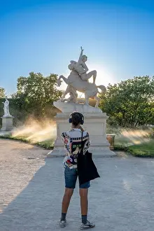 Nightfall Prints: Paris, France - 07 03 2025: One woman take pictures of a statue in Tuileries garden