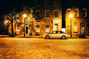 Maryland Prints: Parked car in front of brick buildings on a cobblestone street at night in Fells Point