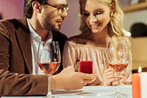 Partial View Prints: partial view of man proposing to girlfriend at table with wine glasses in restaurant