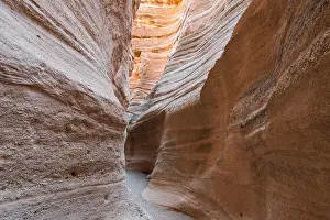Winding Prints: A path winding through the bottom of a slot canyon with sunlight reflecting from the canyon walls at Kasha-Katuwe Tent