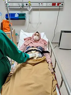 Sterile Prints: Patient laying on bed receiving medical treatment from nurse with green uniform in intensive care unit room at hospital