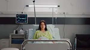 Ward Prints: Patient wearing with nasal oxygen tube looking into camera sitting in bed during online videocall conference