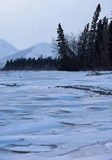 Delta Junction Prints: Patterns in snow on frozen river with trees and mountains in the background on a cloudy winter day in interior Alaska