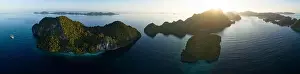 A peaceful sunrise illuminates dramatic limestone islands that rise from Raja Ampat's beautiful seascape. This area has high marine biodiversity