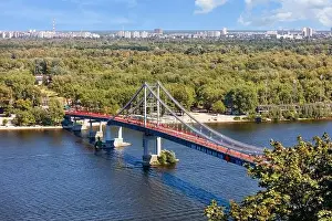 Pedestrian bridge over the Dnipro river to the beach of Trukhaniv island at noon in Kyiv, aerial view, Ukraine