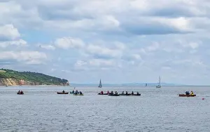 Devon Beaches Prints: People in a canoe on Seaton Bay with the Haven Cliffs Naturist Beach in the background