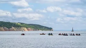People in a canoe on Seaton Bay with the Haven Cliffs Naturist Beach in the background