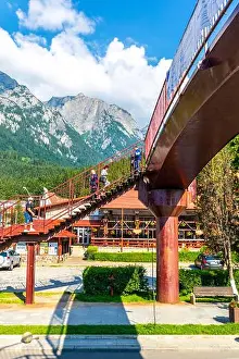 Carpathian Mountains Prints: People crossing red footbridge over main street Bulevardul Libertății and Bucegi Mountains