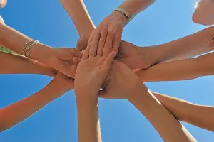 Loyalty Prints: Six people stacking their hands connected against a blue sky