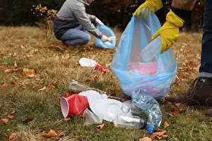 Polluted Prints: People with trash bags collecting garbage in nature, closeup