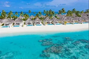 Perfect aerial landscape, luxury tropical resort or hotel with water villas and beautiful beach scenery. Amazing bird eyes view in Maldives, landscape