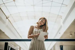 Focused Prints: Persistent Businesswoman Solving Problems with Confidence and a Smile Working on Tablet While Having Phone Call