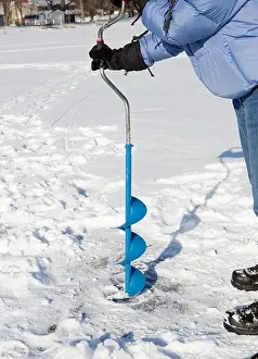 Minnesota Prints: A person drilling a hole into the ice of a frozen lake using an ice auguer (a helical screw blade)