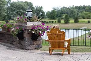 Unwinding Prints: Person relaxing in a garden chair with their back to the camera overlooking open countryside and a small lake
