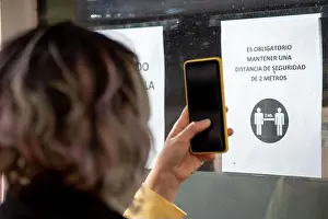 Measures Prints: A person taking a picture of a sign about safety measures to stop the coronavirus pandemic in Spain