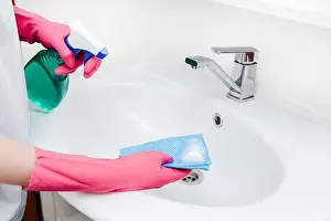 Cleaner Prints: Person wearing pink gloves uses cleaning spray and sponge to clean white bathroom sink