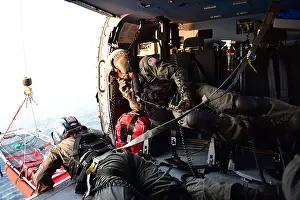 Petty Officer 2nd Class Benjamin Davis retrieves a rescue basket while Petty Officer 2nd Class Tyler Johnson checks