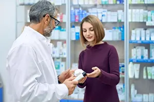 Remedy Prints: Pharmacist offering female customer medical products in drugstore