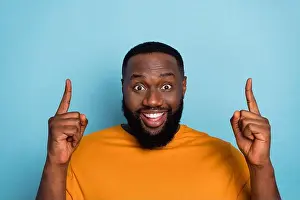 Recommendation Prints: Photo of cute impressed guy wear orange t-shirt pointing up empty space isolated blue color background