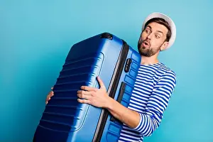 Big Blue Prints: Photo of handsome guy traveler hold big suitcase plane flight weight allowance too heavy bag feel back pain wear