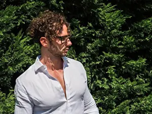 Curly Hair Prints: Photo of a man with curly hair and glasses standing in front of a bush