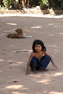 Angkor Wat Prints: Photograph of a cute Cambodian girl and dog playing near a temple in Siem Reap
