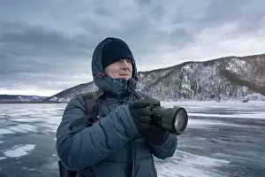 Frigid Prints: A photographer is capturing icy landscapes in winter gear amidst snowy mountains and frosty scenery