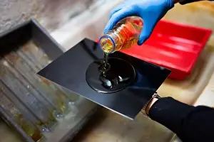 Photographer pouring collodion solution on the black iron plate. Wet plate collodion process