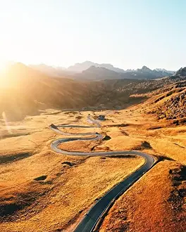 Picturesque aerial view on winding road in autumn mountain valley at sunset