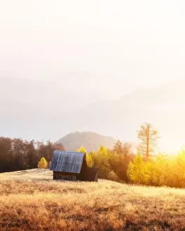 Picturesque autumn meadow with wooden house and red beech trees in the Carpathian mountains, Ukraine. Landscape photography