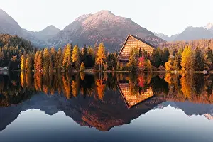 Picturesque autumn view of lake Strbske pleso in High Tatras National Park, Slovakia. Clear water with reflections of orange larch and high mountains