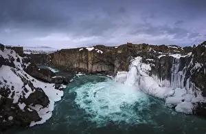 Sky Mountain Prints: Picturesque drone view of Aldeyjarfoss waterfall falling from rough snowy cliff against cloudy evening sky in winter