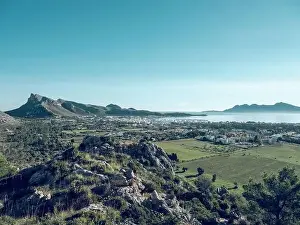 Picturesque drone view of Pollensa town located amidst green agricultural fields