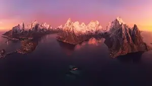 Picturesque scenery from drone of snowy mountains and calm sea under cloudless sky in Norway in evening