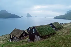 Picturesque view of tradicional faroese grass-covered houses in the village Bour. Drangarnir and Tindholmur sea stacks on background. Vagar island, Fa