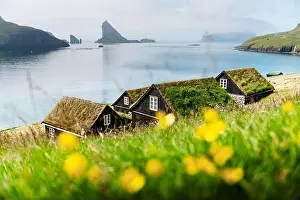 Picturesque view of tradicional faroese grass-covered houses in the village Bour. Drangarnir and Tindholmur sea stacks on background