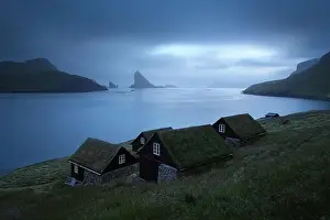 Picturesque view of tradicional faroese grass-covered houses in the village Bour. Drangarnir and Tindholmur sea stacks on background