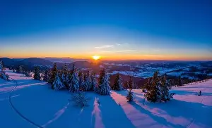 Wintersport Prints: Picturesque winter panorama of mountain hills covered with snow and fir trees on a sunny clear day with the sun