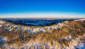 Wintersport Prints: Picturesque winter panorama of mountain hills covered with snow and fir trees on a sunny clear day with the sun