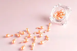 Concentrated Prints: pink cosmetic capsules on pink background skattered out from a jar