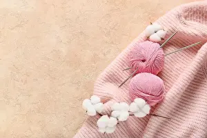 Thread Prints: Pink yarn balls and knitting needles with cotton bolls on a soft knitted sweater