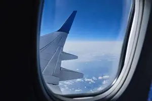 Plane wing in porthole. Aerial sky horizon view from airplane window