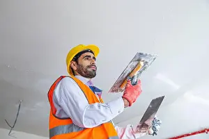 Trowel Prints: A plasterer in construction wears overalls and a hat